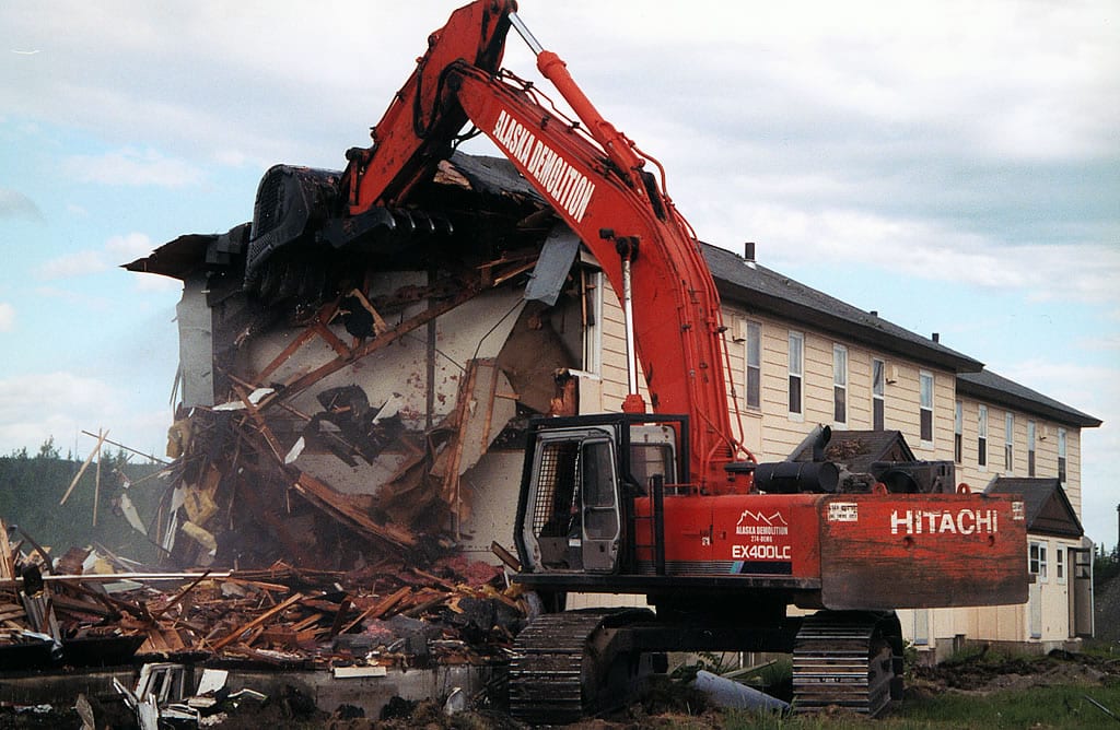 Excavator demolishing house