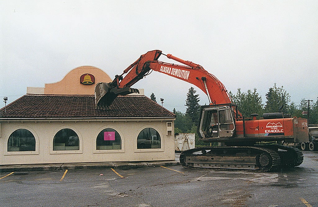 Excavator tearing down building